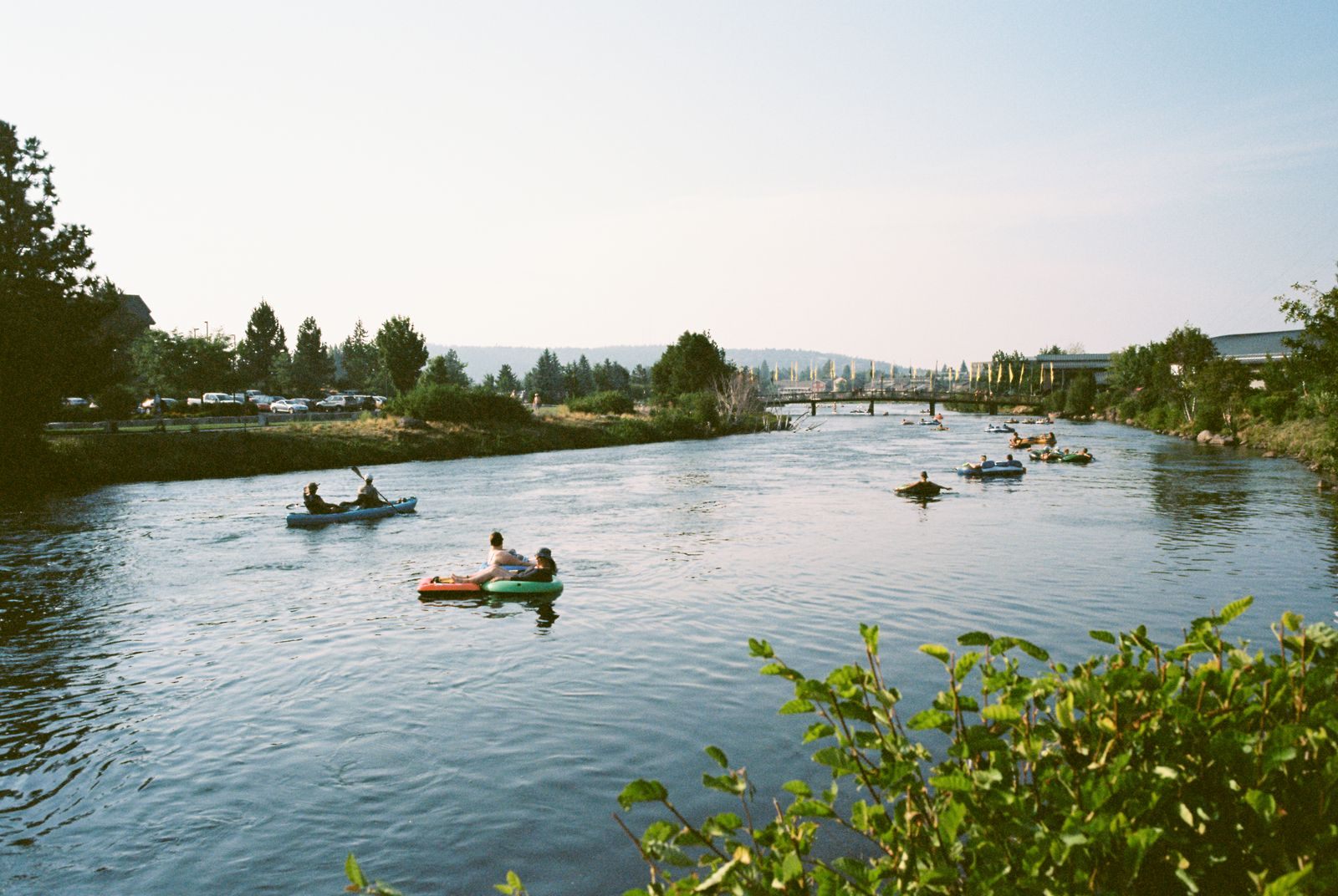 People paddling kayaks on the calm Deschutes River in Bend on a sunny day