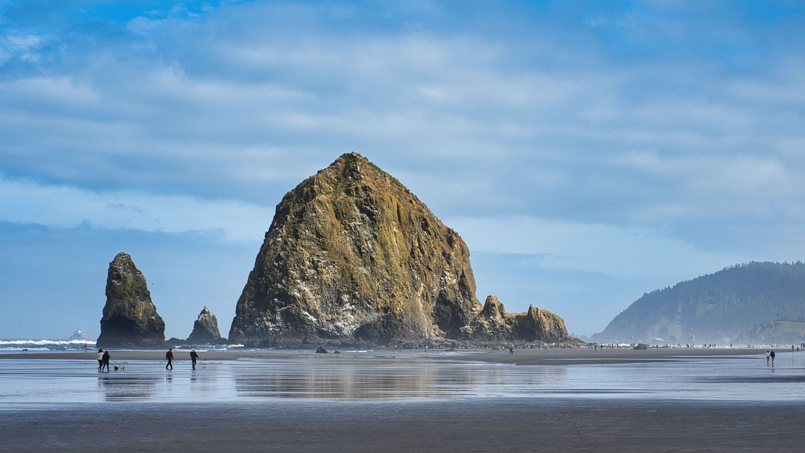 Haystack Rock and smaller sea stacks on the wet sand at Cannon Beach, a highlight of things to do in Oregon coast towns
